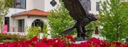 Photo of Bronze Red Hawk Statue with red azaleas