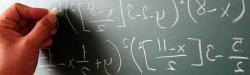Hand writing mathematical formulas on a blackboard.
