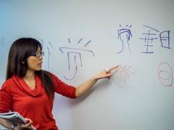 Professor Wing Shan Ho in front of white board with Chinese characters written on board