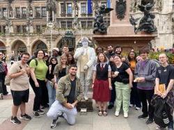 a group of students stands together for a photo next to a statue in Munich