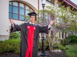 Montclair student with cap and gown on campus