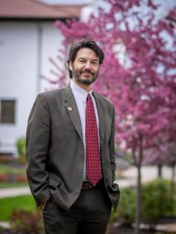Montclair State University President Jonathan Koppell poses by a blooming tree on campus.