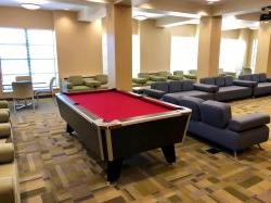 Another picture of the common area in Sinatra Hall featuring a pool table and some couches and chairs.